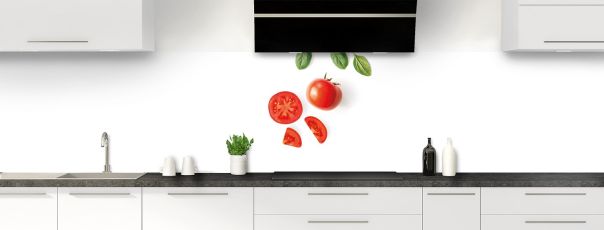 Une crédence très épurée avec une tomate entière, des quartiers de tomate et quelques feuilles de basilic